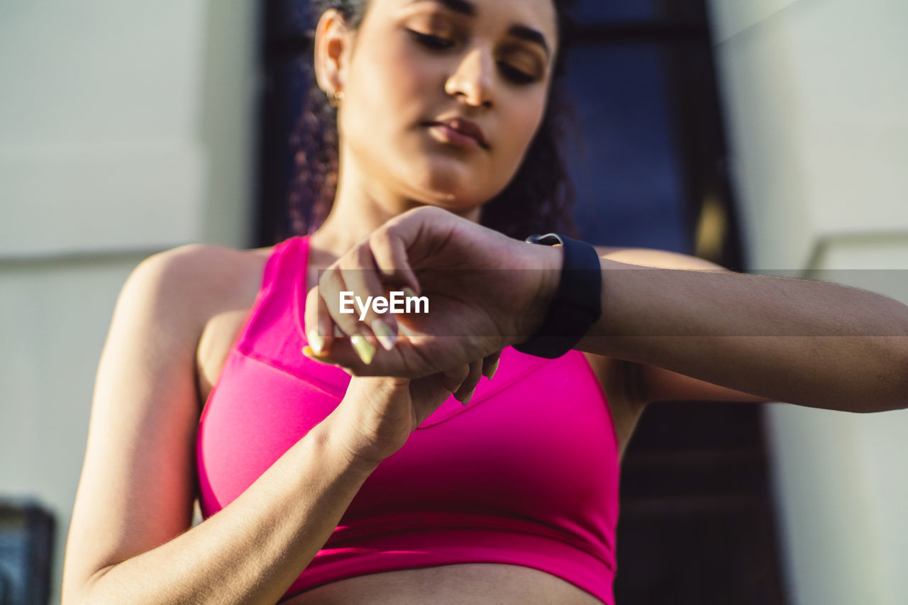 Curly young woman, wearing a fitness watch for running.