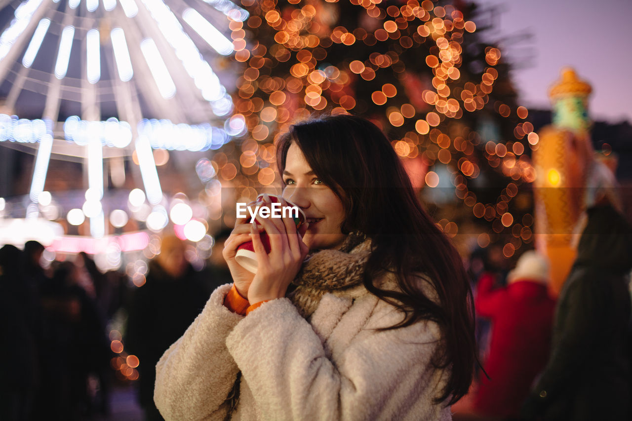 Happy teenage girl drinking mulled wine in christmas market