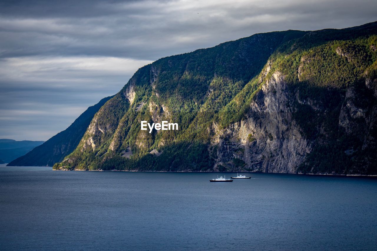 Scenic view of sea by mountains against sky