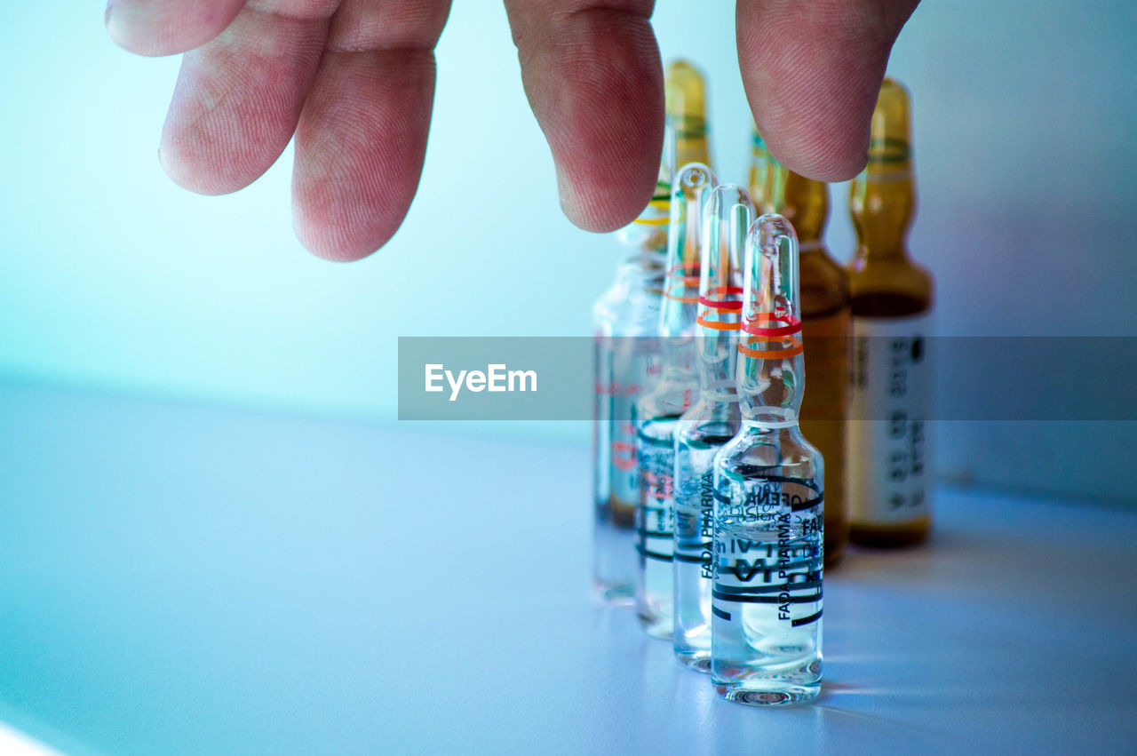 hand, blue, one person, indoors, bottle, water, adult, close-up, research, healthcare and medicine, drink, science, holding, scientific experiment, focus on foreground, soft drink, laboratory