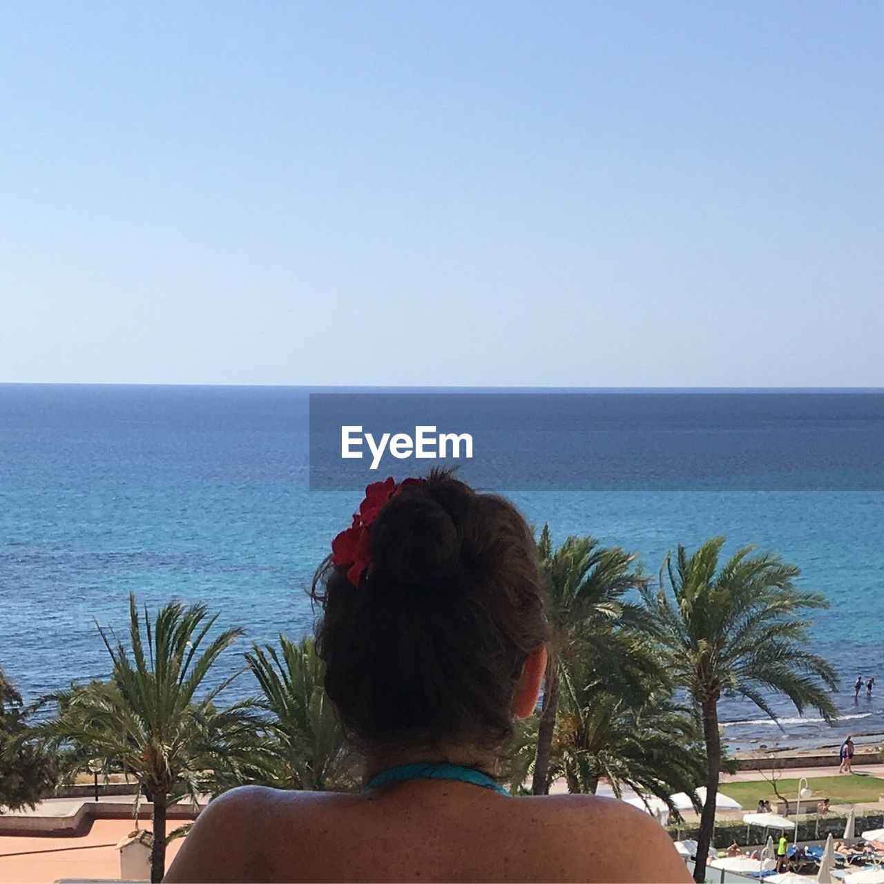 REAR VIEW OF WOMAN STANDING ON BEACH AGAINST CLEAR SKY