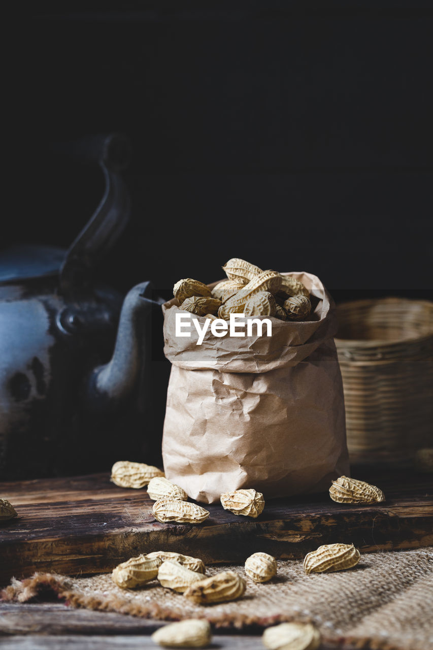 Close-up of peanuts in paper bag with kettle on table