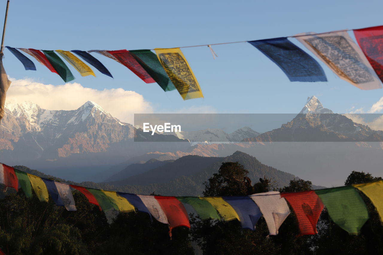 MULTI COLORED FLAGS ON MOUNTAINS AGAINST SKY