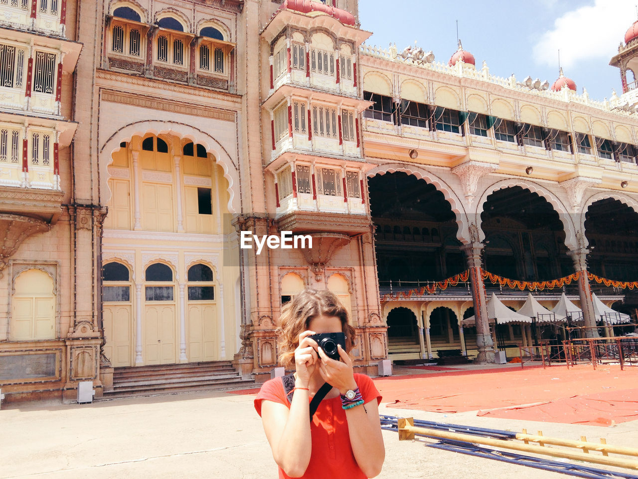 Young woman photographing while standing against historic building