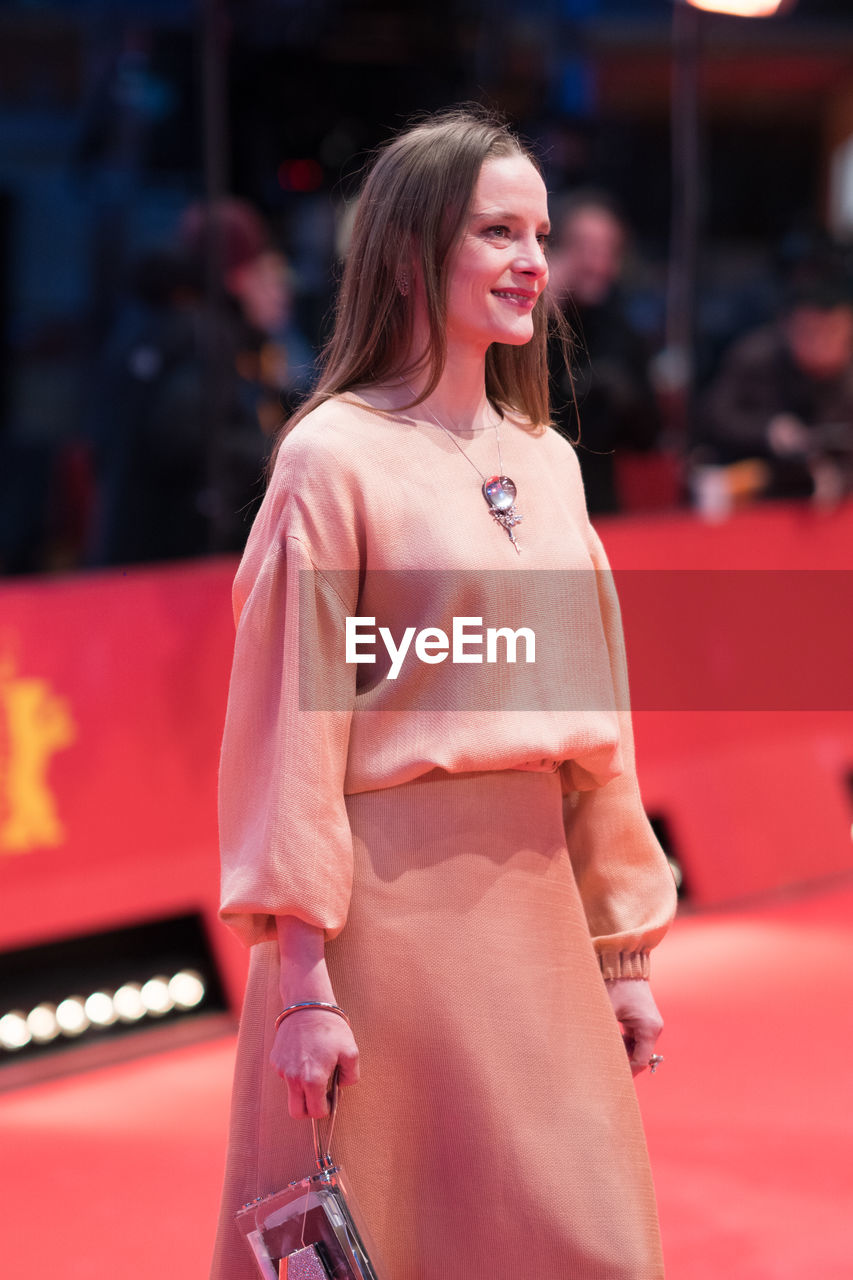 SMILING YOUNG WOMAN WITH ARMS RAISED