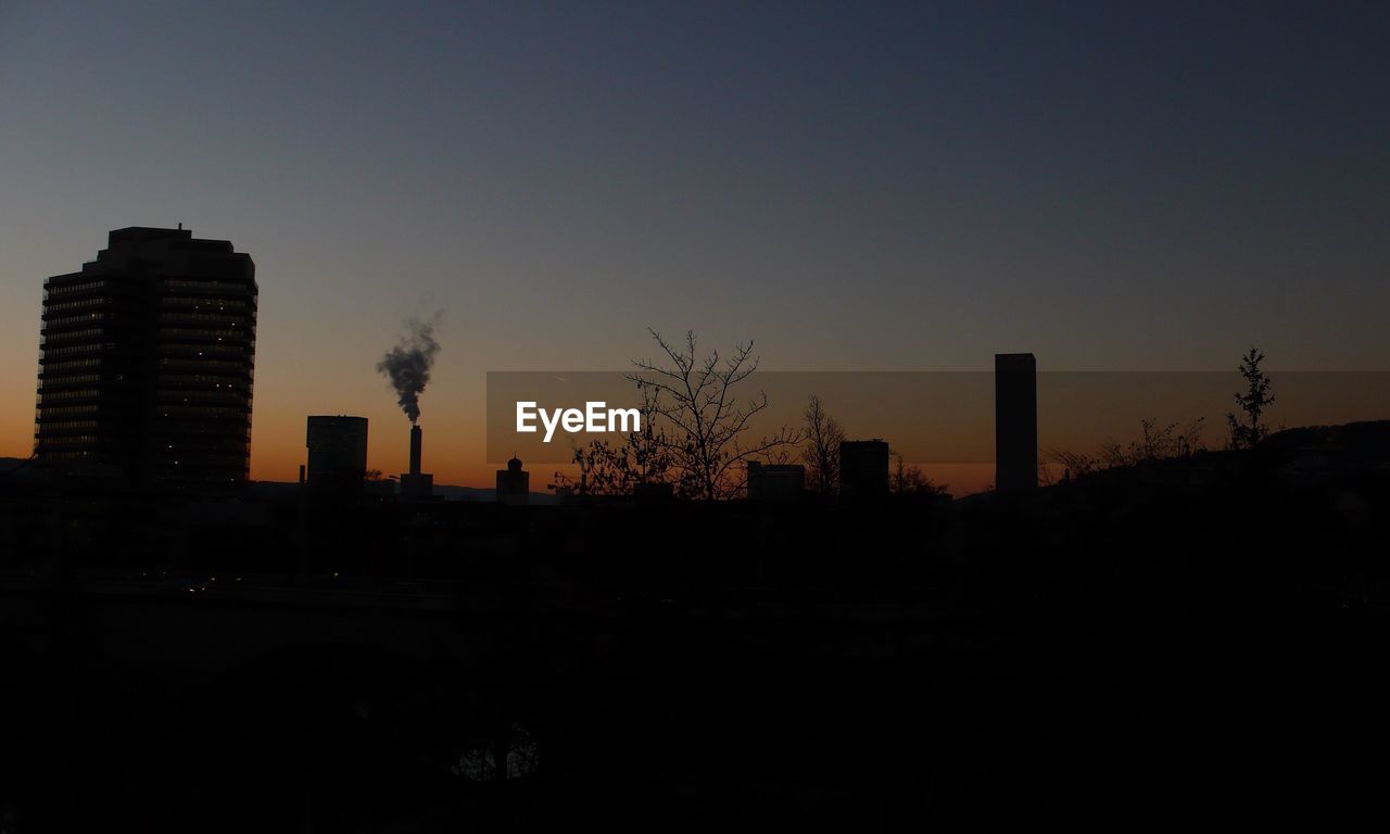 SILHOUETTE OF CITY AGAINST SKY AT DUSK