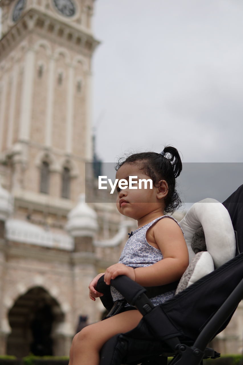 Portrait of little girl looking away while sitting in baby stroller