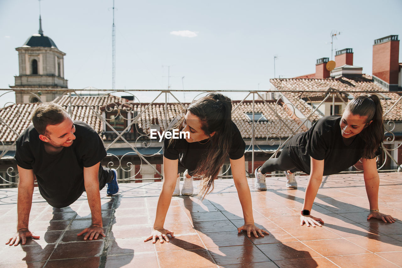 Three people doing push-ups on a rooftop