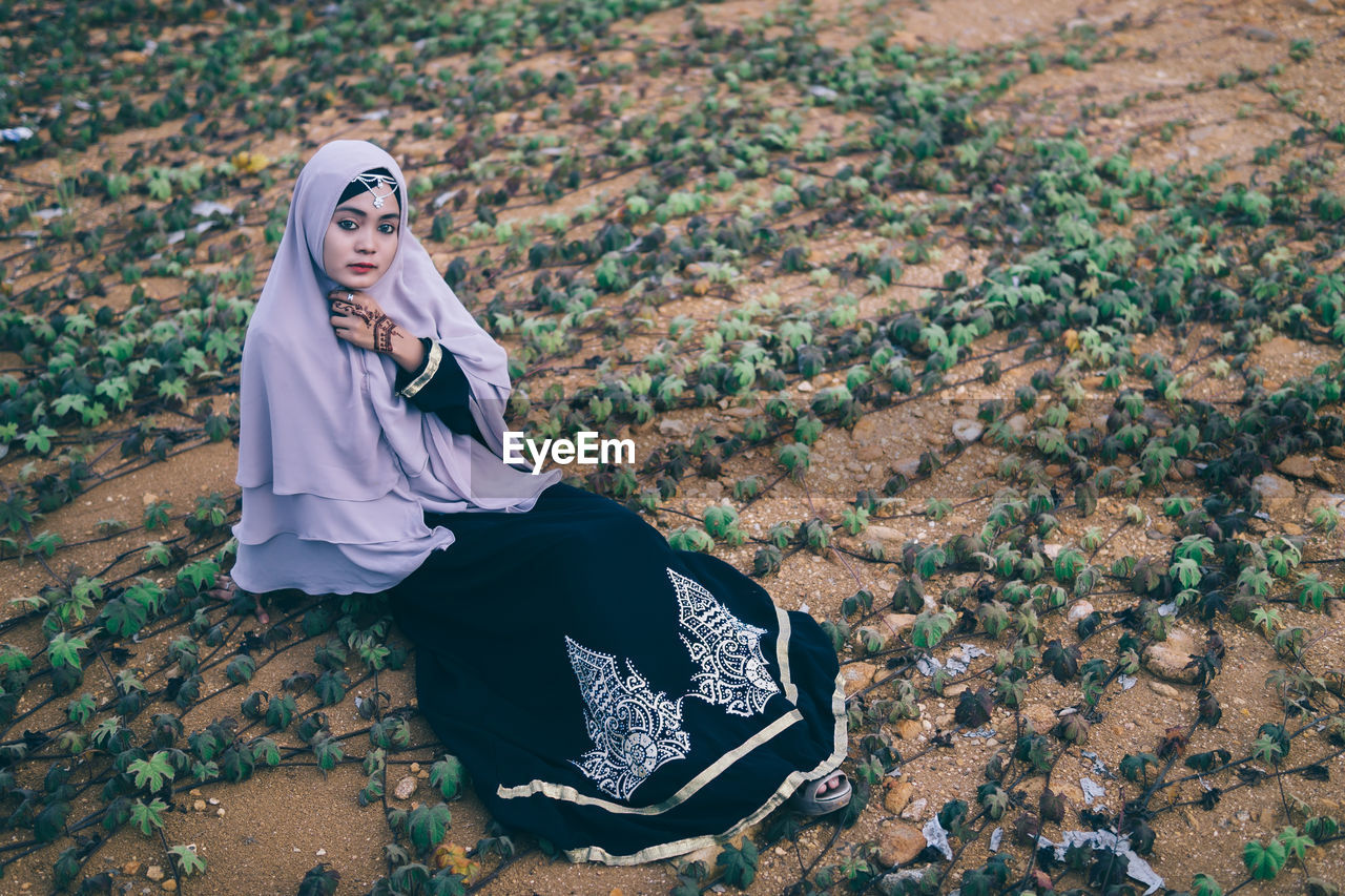 Portrait of young woman in hijab sitting outdoors