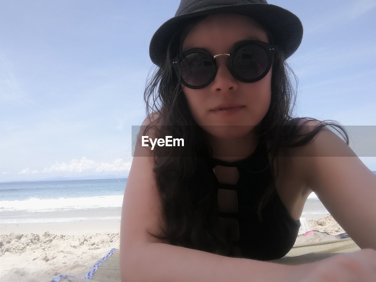 PORTRAIT OF YOUNG WOMAN IN SUNGLASSES AGAINST SKY