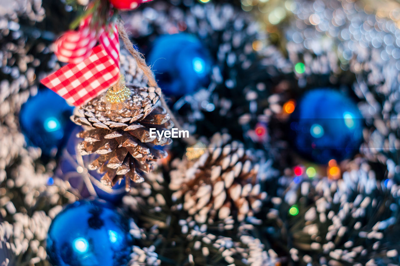 Close-up of pine cone by gift on christmas tree