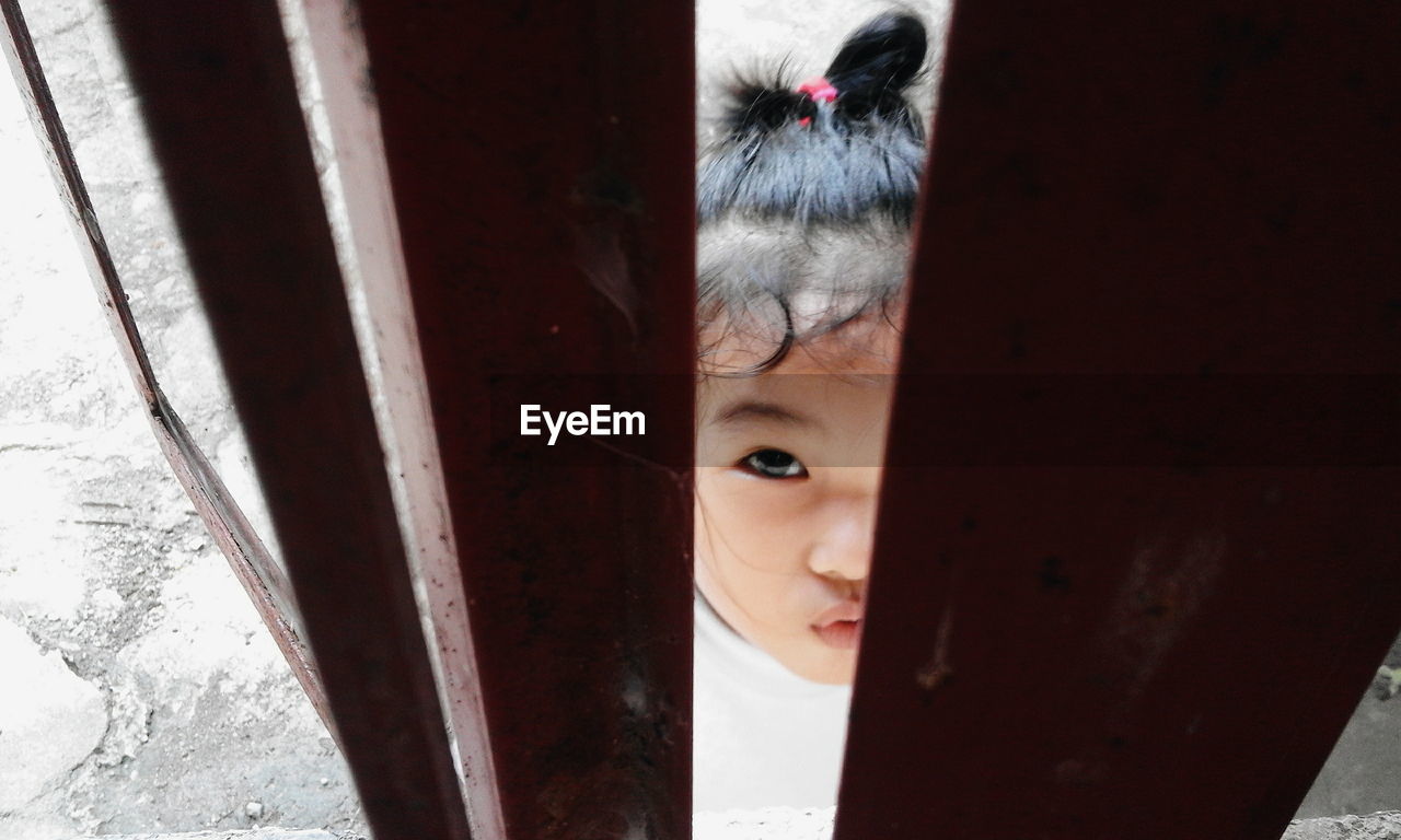 Portrait of cute girl seen through window