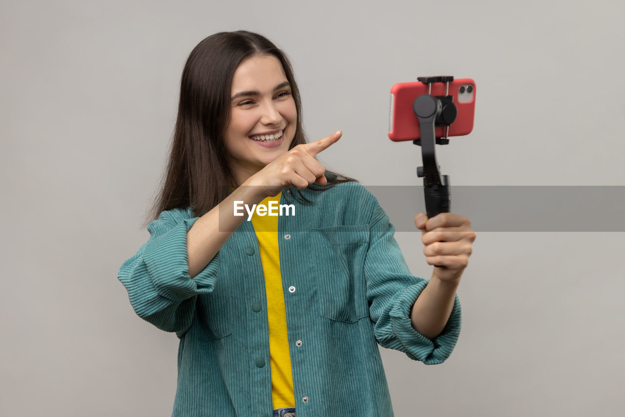 portrait of smiling young woman holding knife against white background