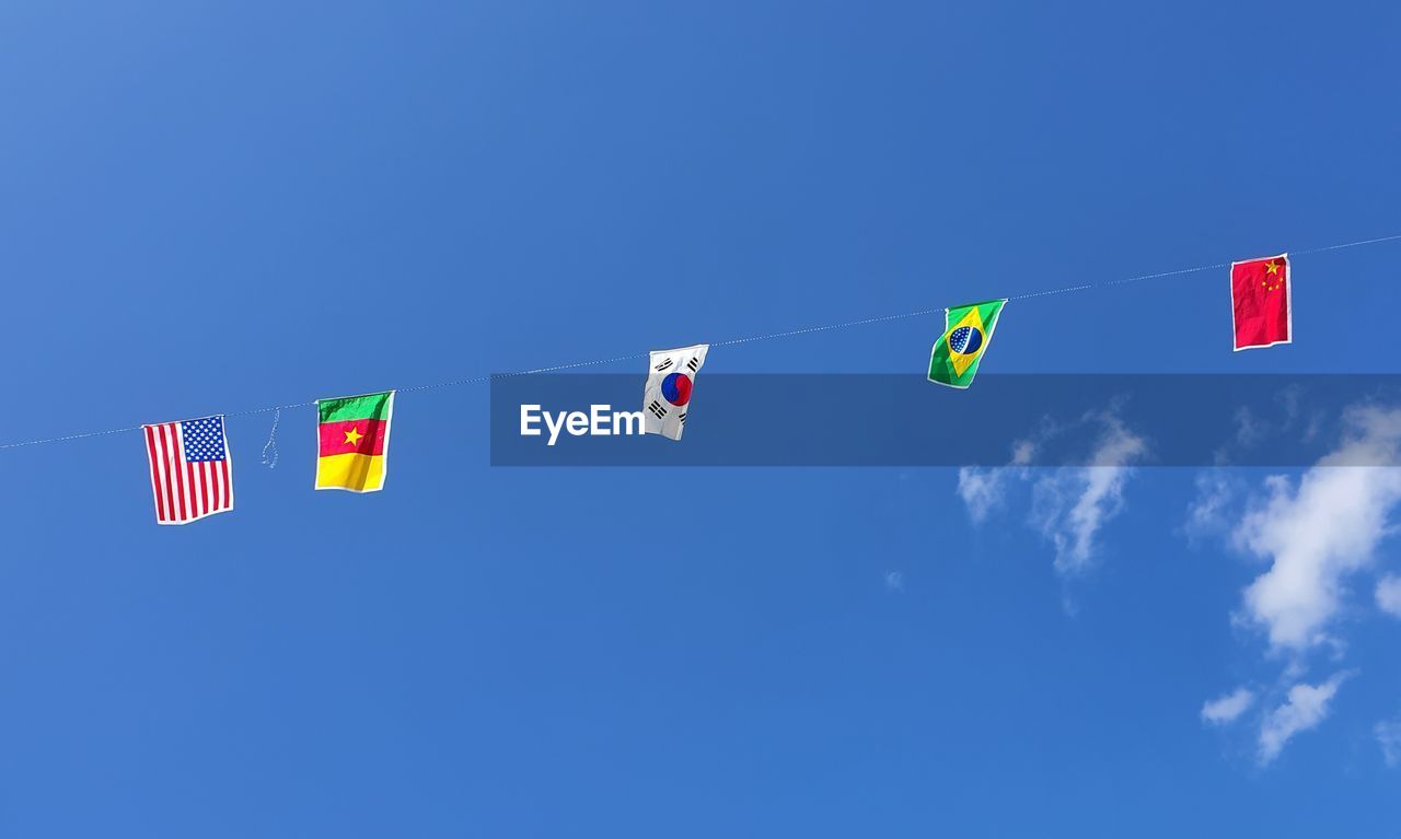 LOW ANGLE VIEW OF FLAGS AGAINST BLUE SKY