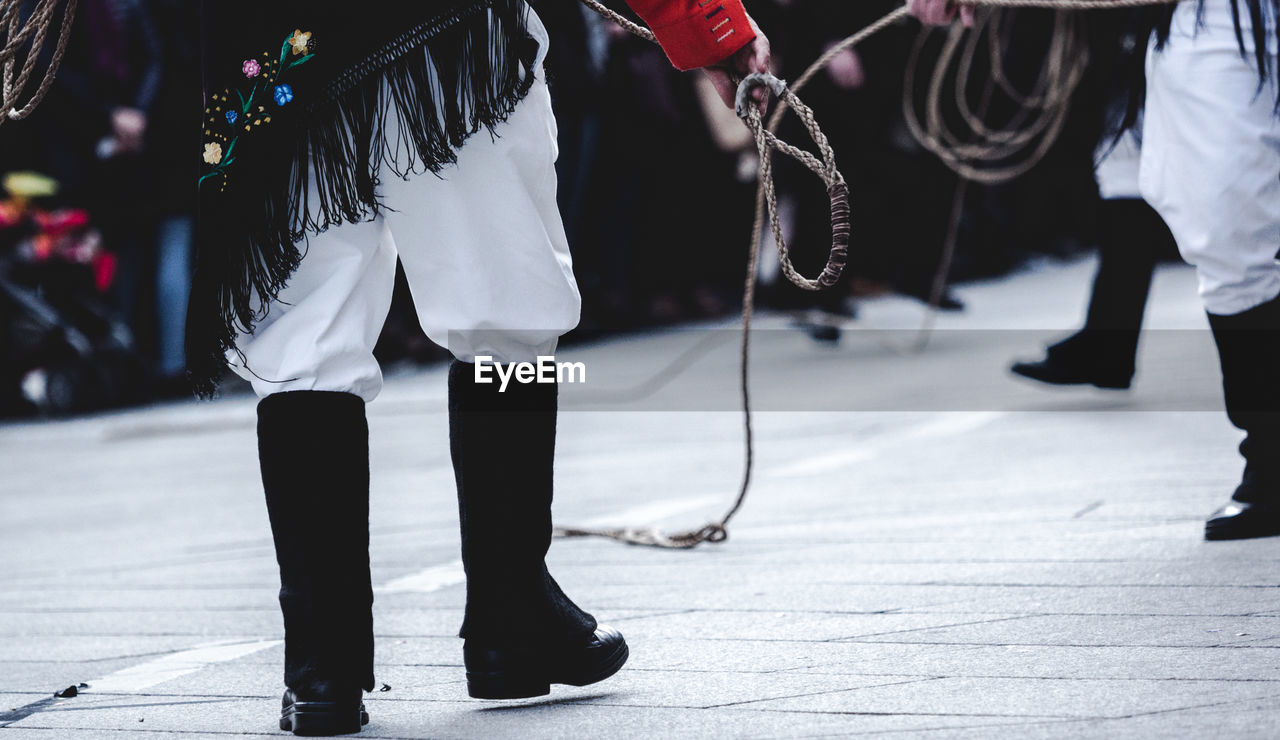 Low section of people in costume with rope standing in event