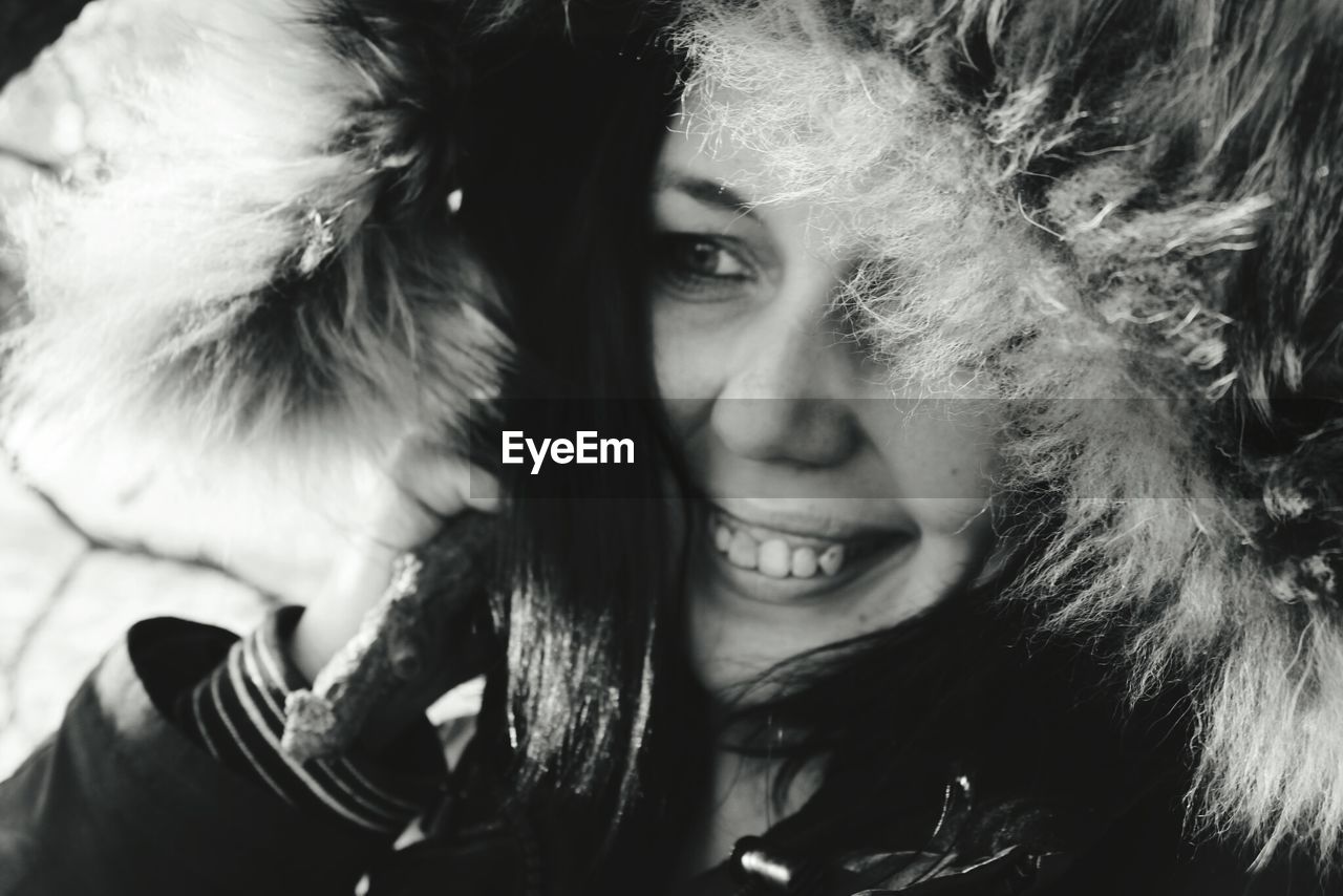 Close-up of thoughtful woman smiling while wearing warm clothing