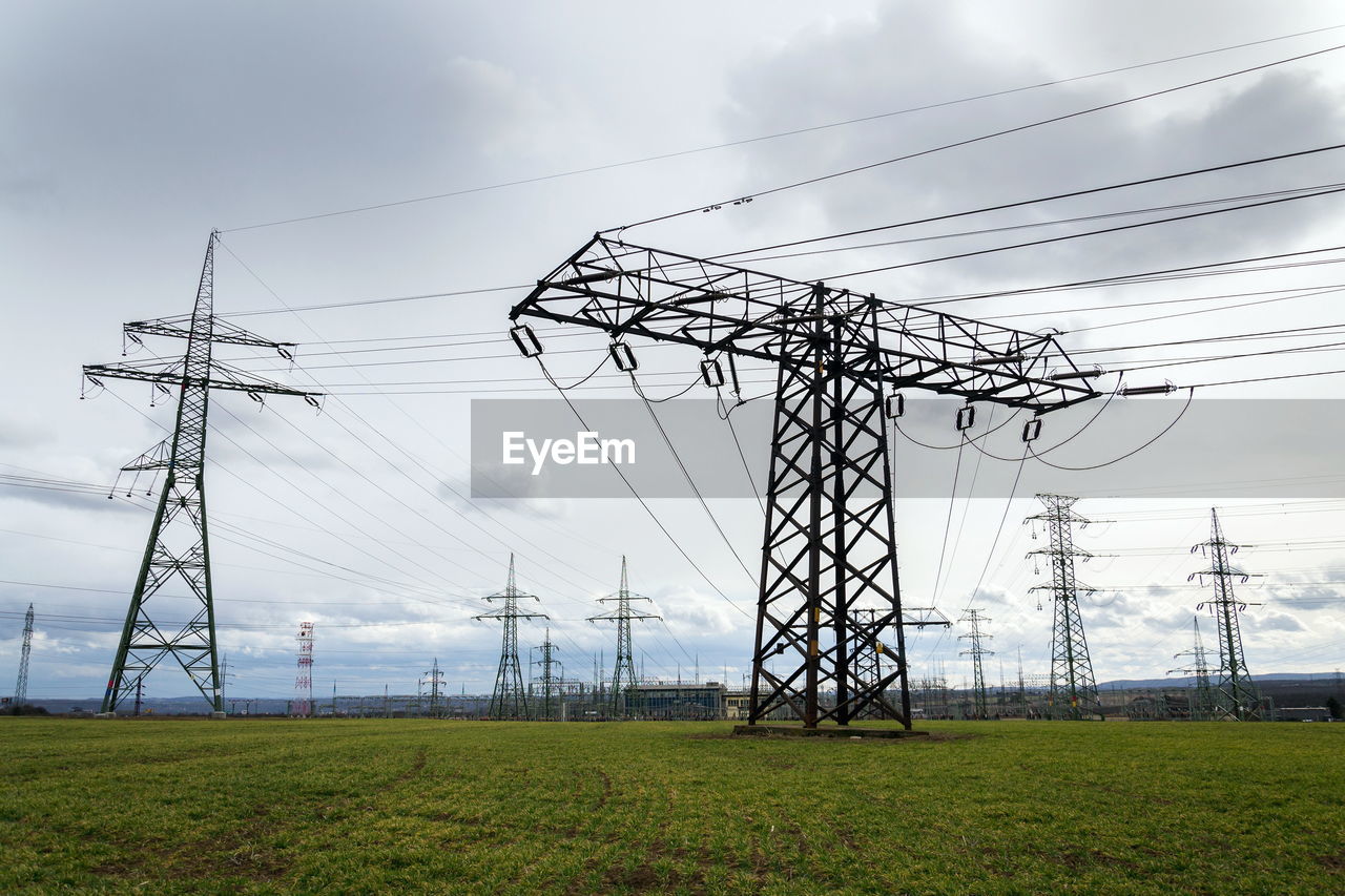 ELECTRICITY PYLON ON FIELD AGAINST SKY