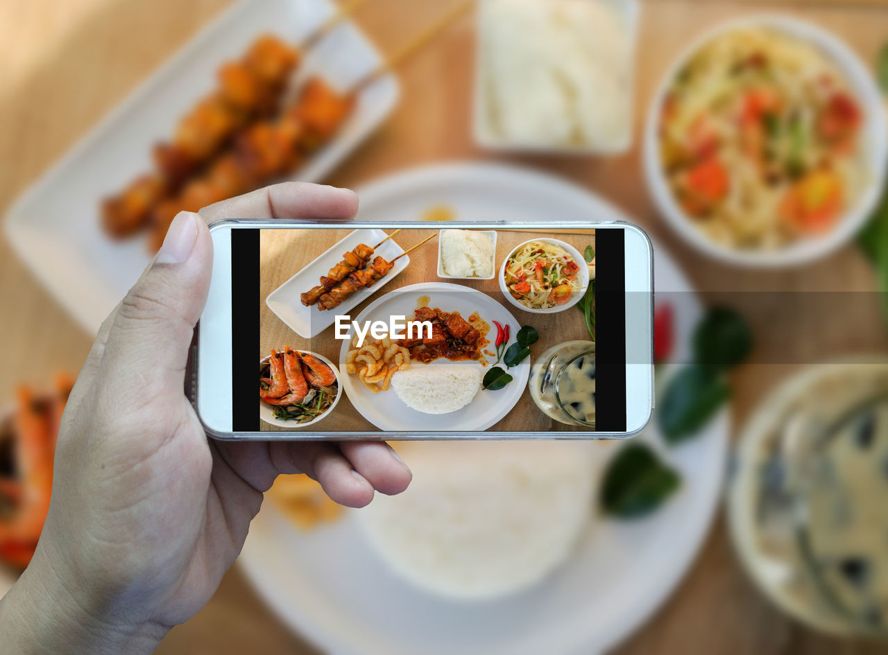 Cropped hand of person photographing food through smart phone