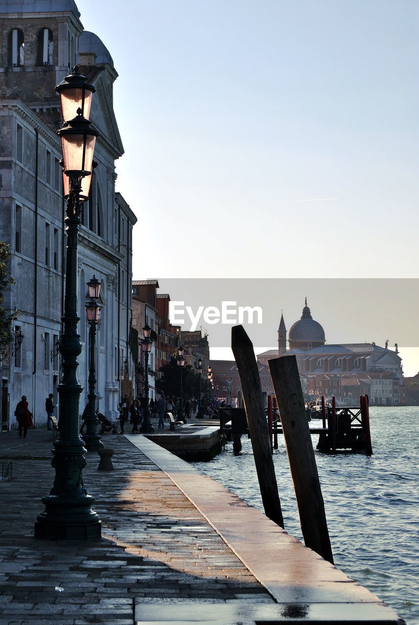 Buildings by sea against clear sky