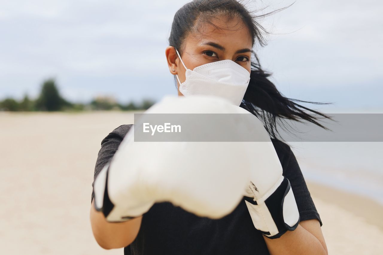 Portrait of woman wearing surgical mask and boxing gloves.
