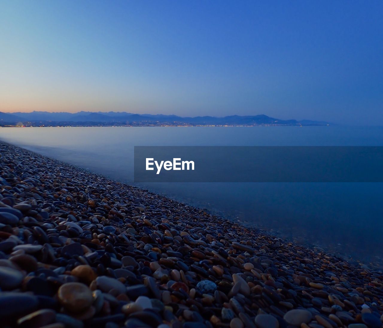 Close-up of pebbles on beach against clear sky