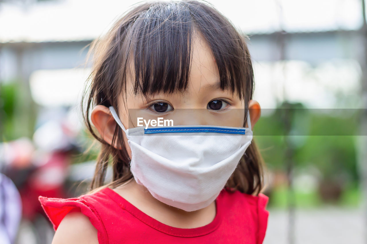 Portrait of cute girl wearing mask outdoors