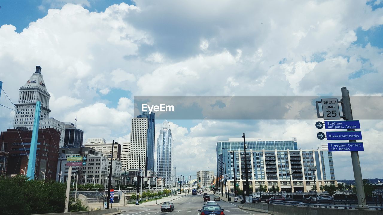 City street amidst buildings against cloudy sky