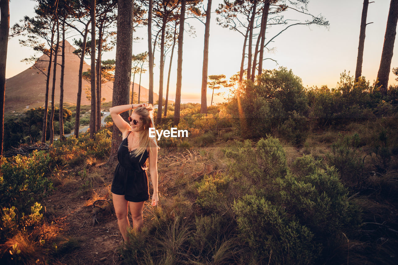 Woman standing against trees during sunset