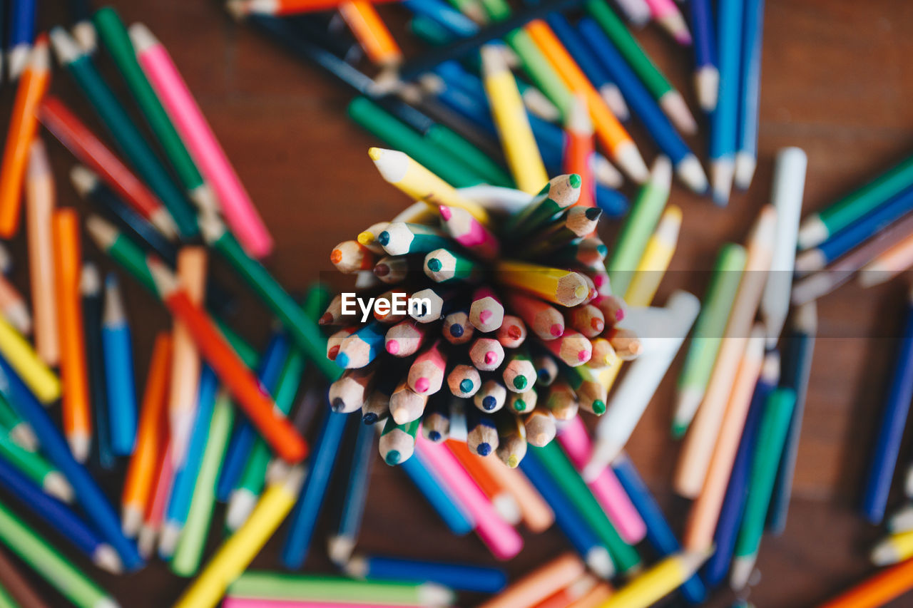 Close-up of multi colored pencils in cup on table