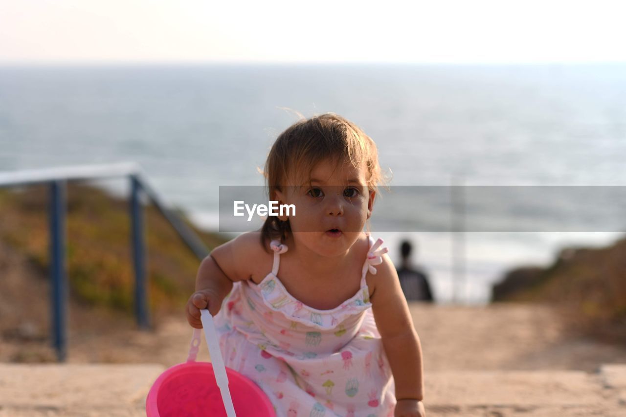 Portrait of cute girl at beach against sky