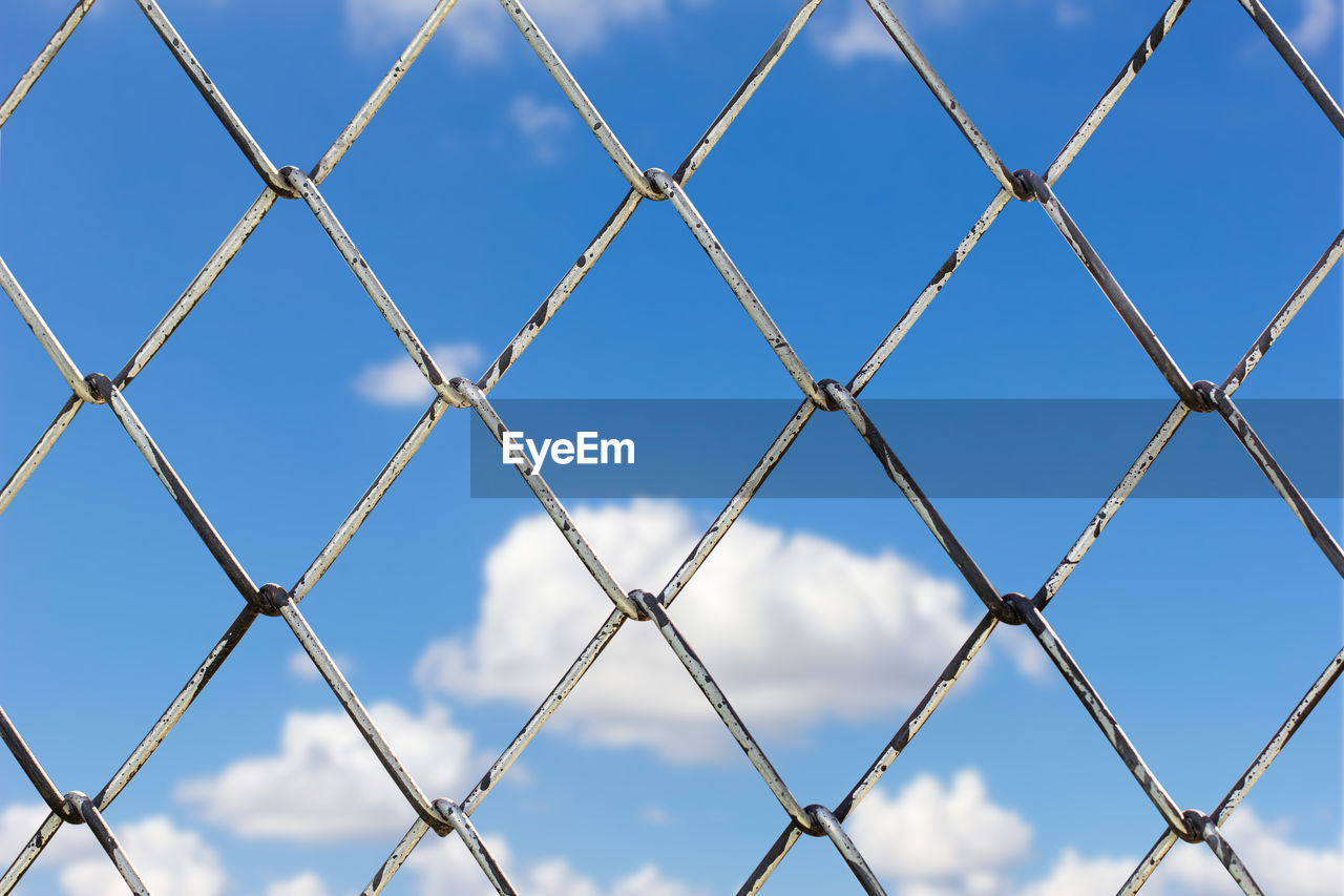 Low angle view of chainlink fence against sky