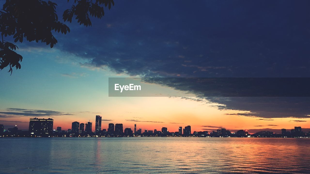 SEA AND BUILDINGS AGAINST SKY DURING SUNSET