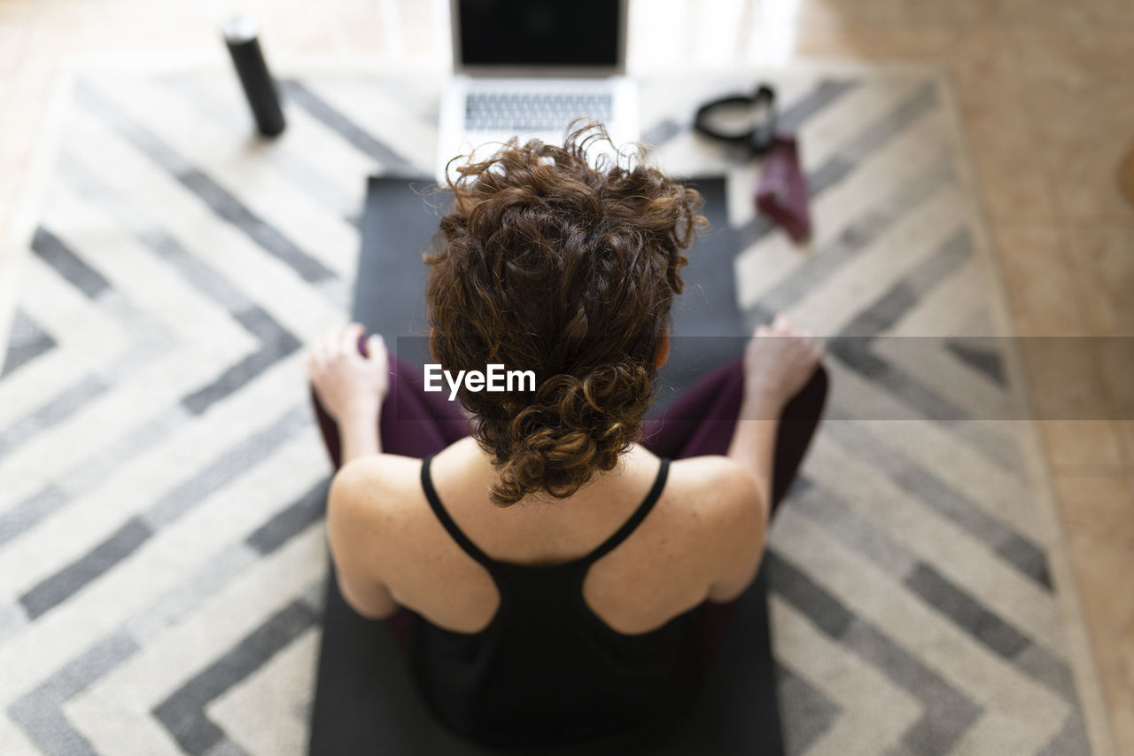 Woman on exercise mat practicing yoga at home