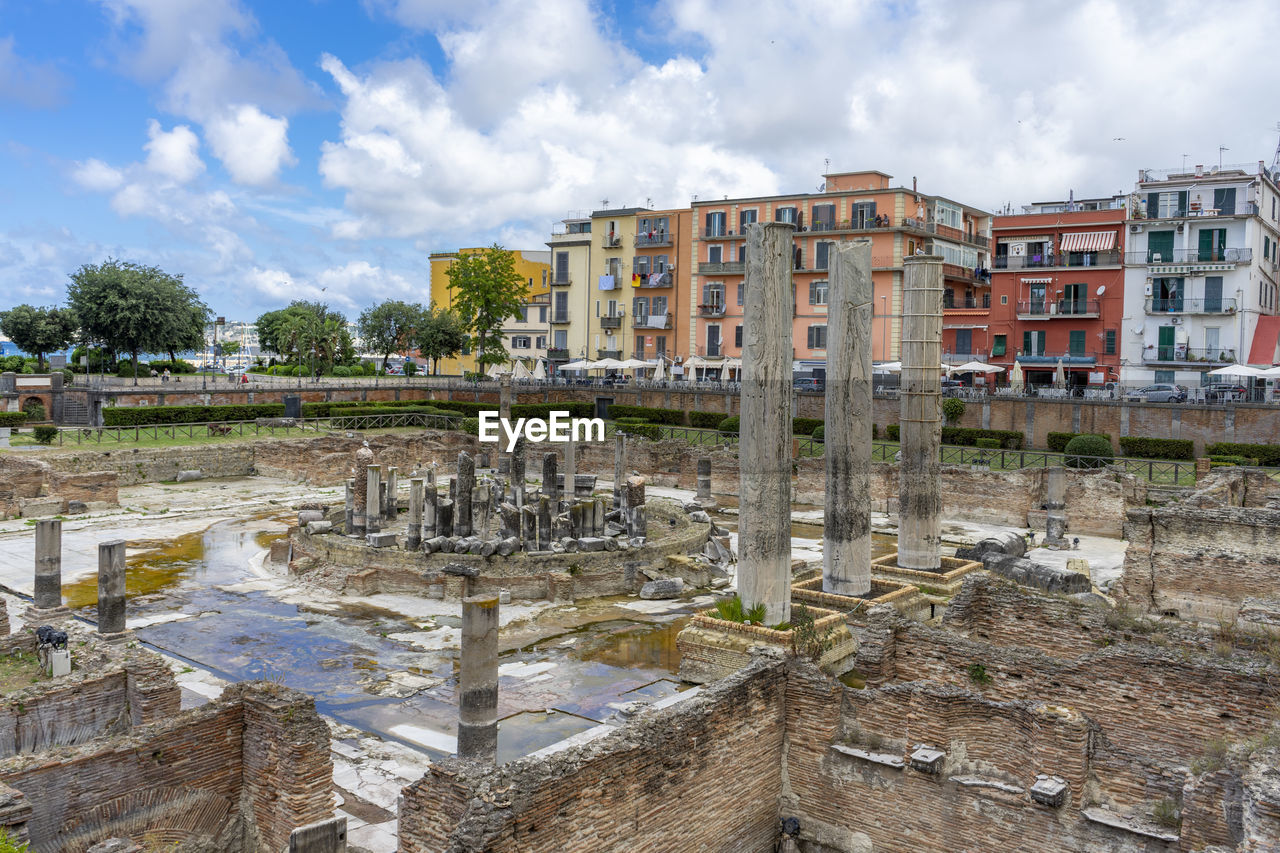 OLD BUILDINGS BY RIVER AGAINST SKY