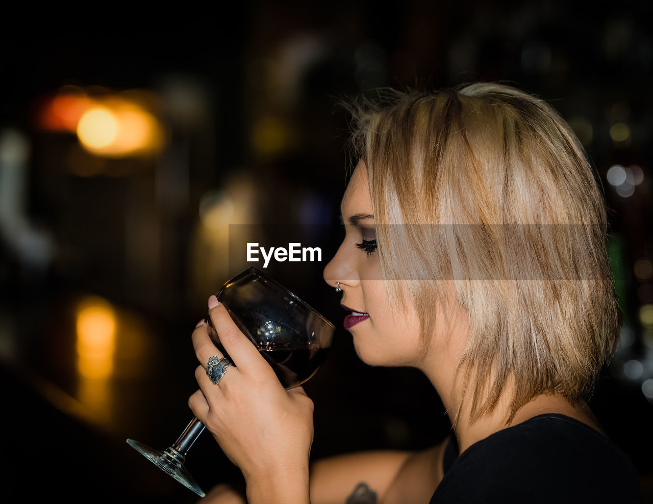 Side view of woman drinking wine at bar