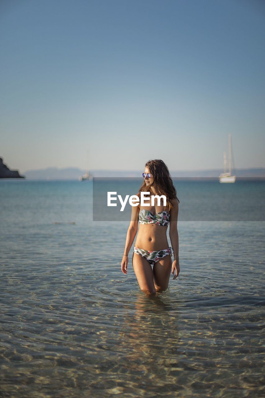 YOUNG WOMAN STANDING IN SEA