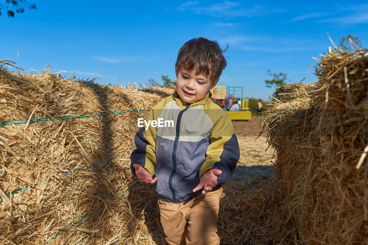 Cute boy running around in the hay stacks on halloween