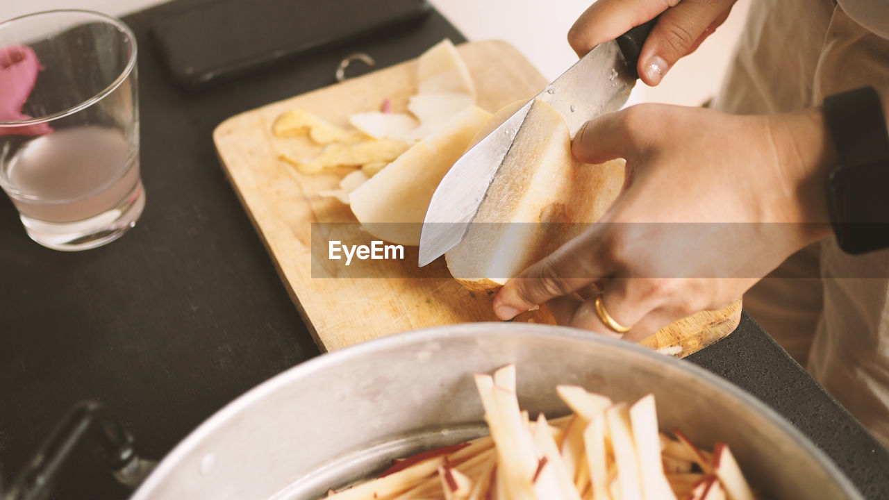 MIDSECTION OF PERSON PREPARING FOOD AT KITCHEN