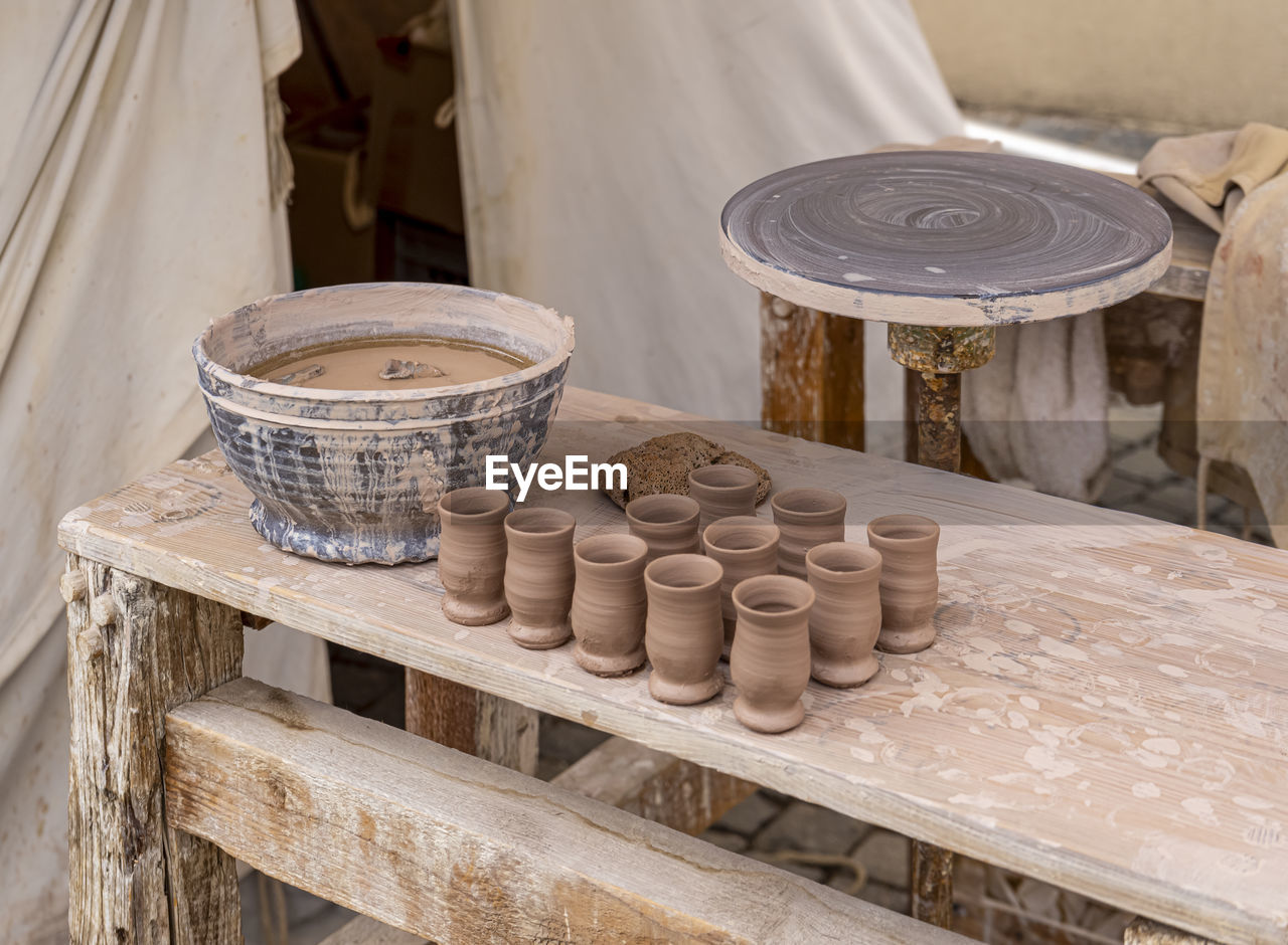 Traditional ceramic manufacturing with throwing table, beakers and bowl on wooden table