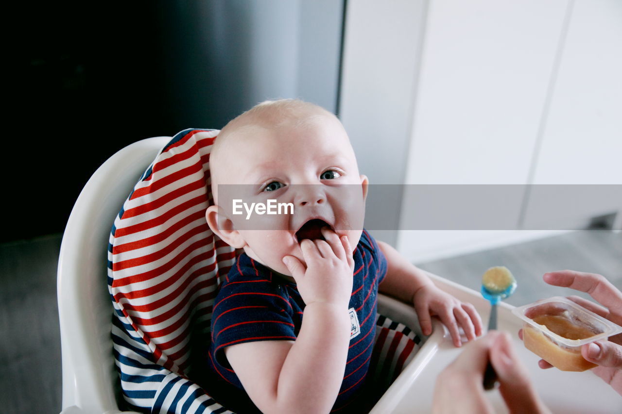 Cropped image of parent feeding food to cute baby boy