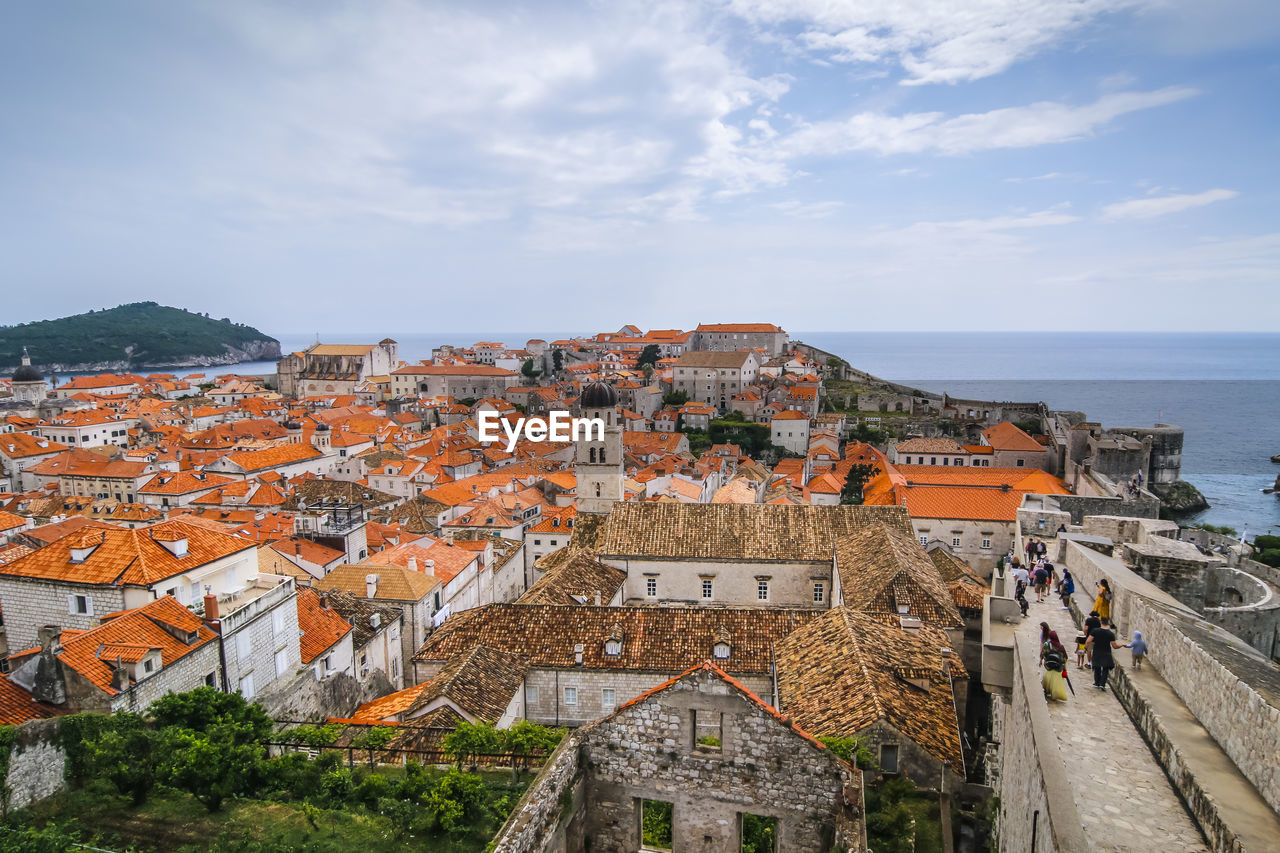 High angle view of townscape by sea against cloudy sky