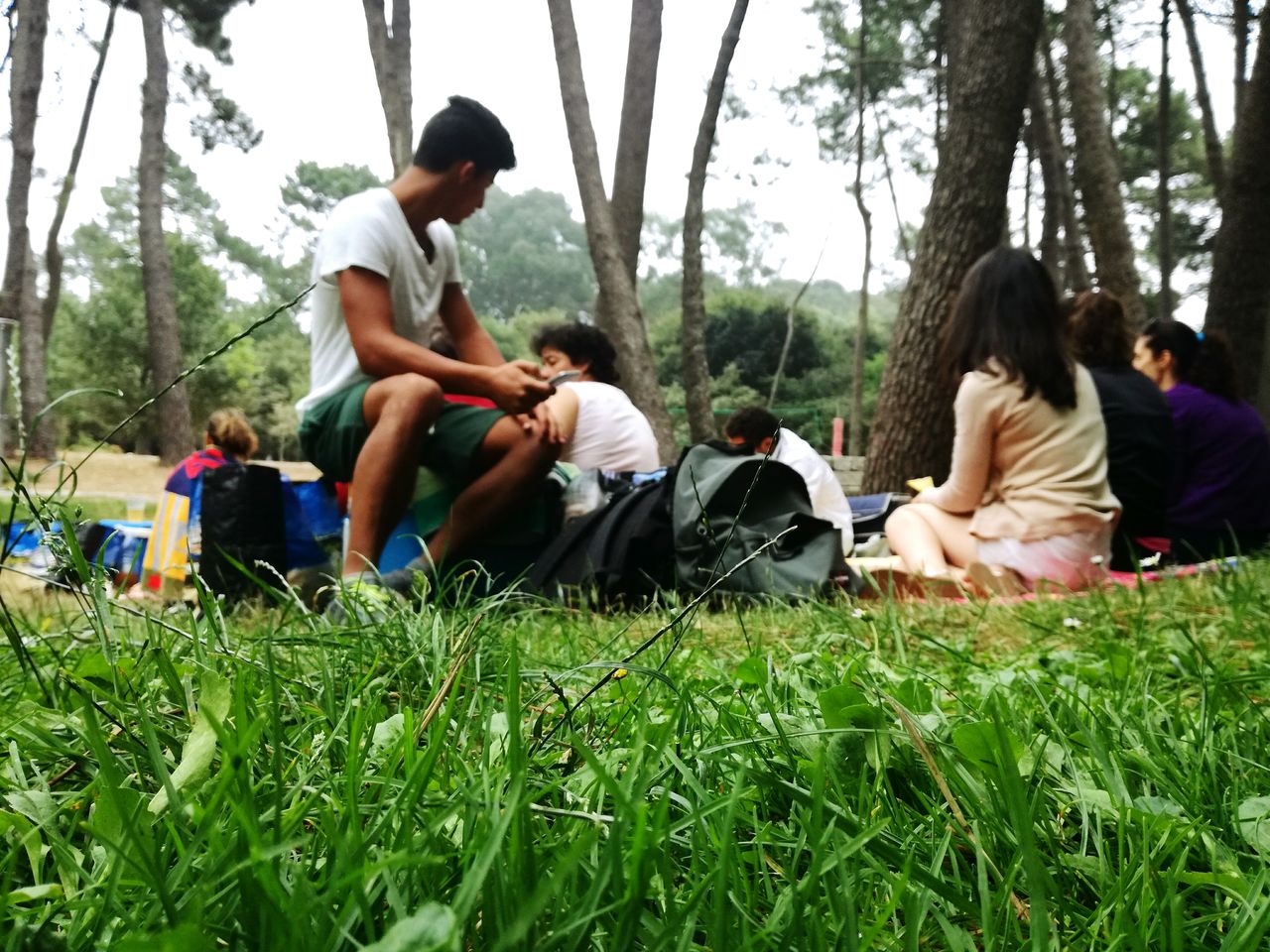 FRIENDS SITTING ON GRASSY FIELD IN PARK