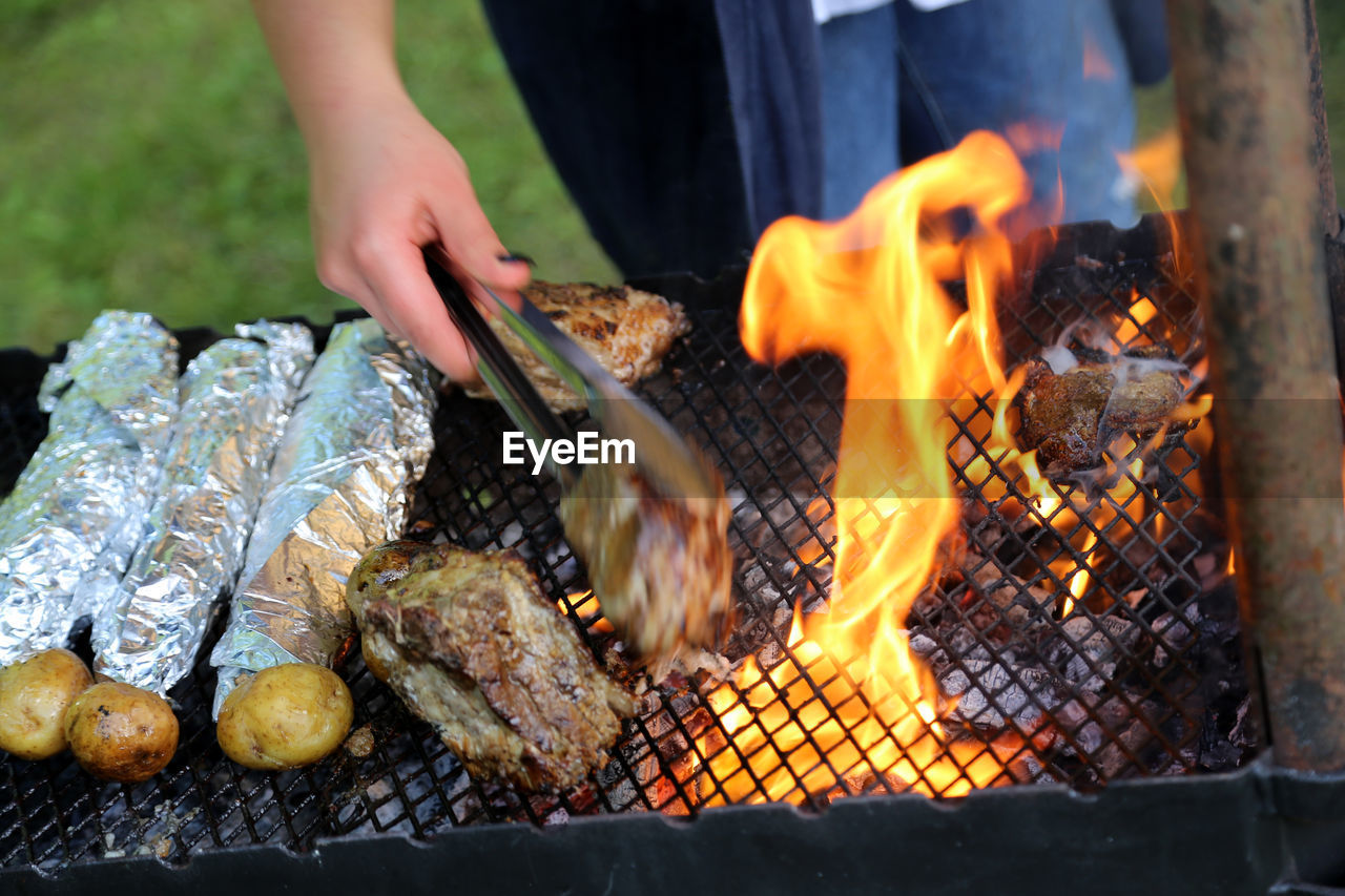 Midsection of man preparing meat on barbecue