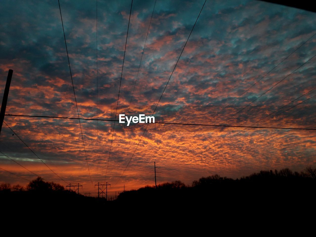 SILHOUETTE OF ELECTRICITY PYLONS AGAINST DRAMATIC SKY