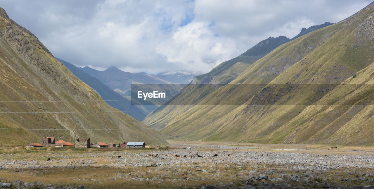 Scenic view of landscape and mountains against cloudy sky