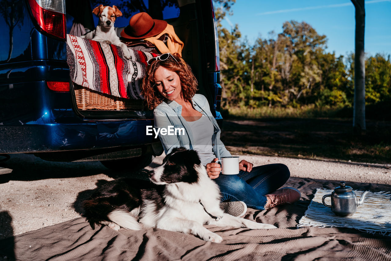 Smiling woman with dog sitting on blanket