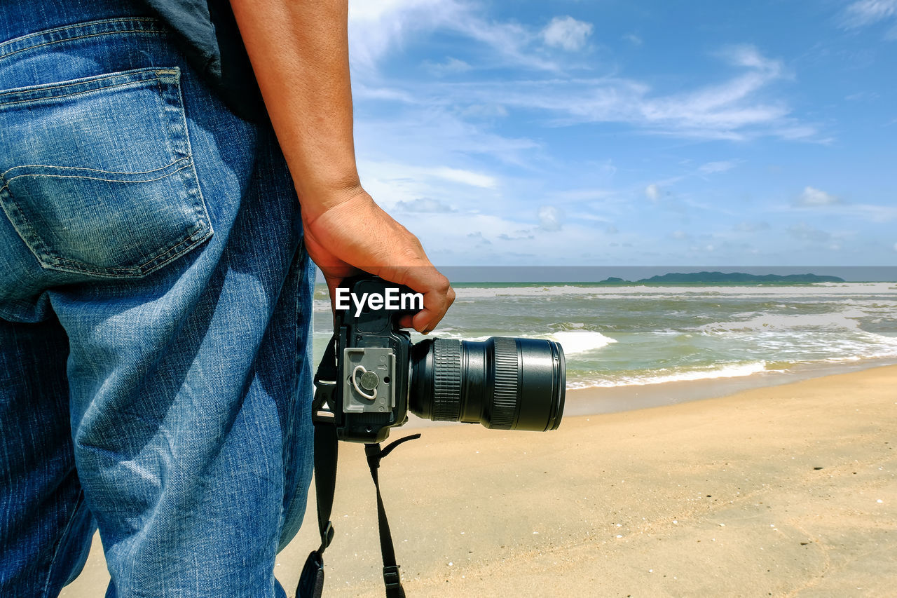 Man holding camera on beach