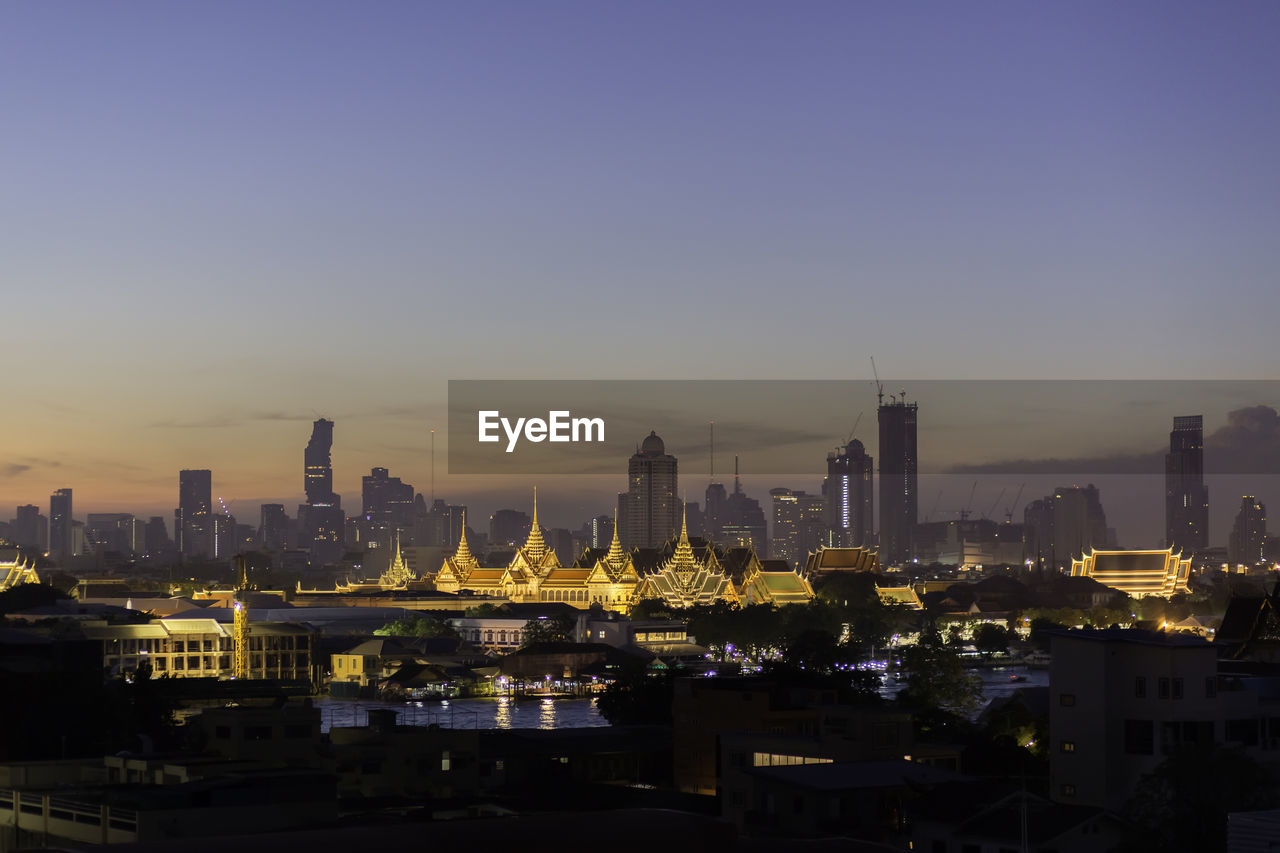 Illuminated cityscape against clear sky at night