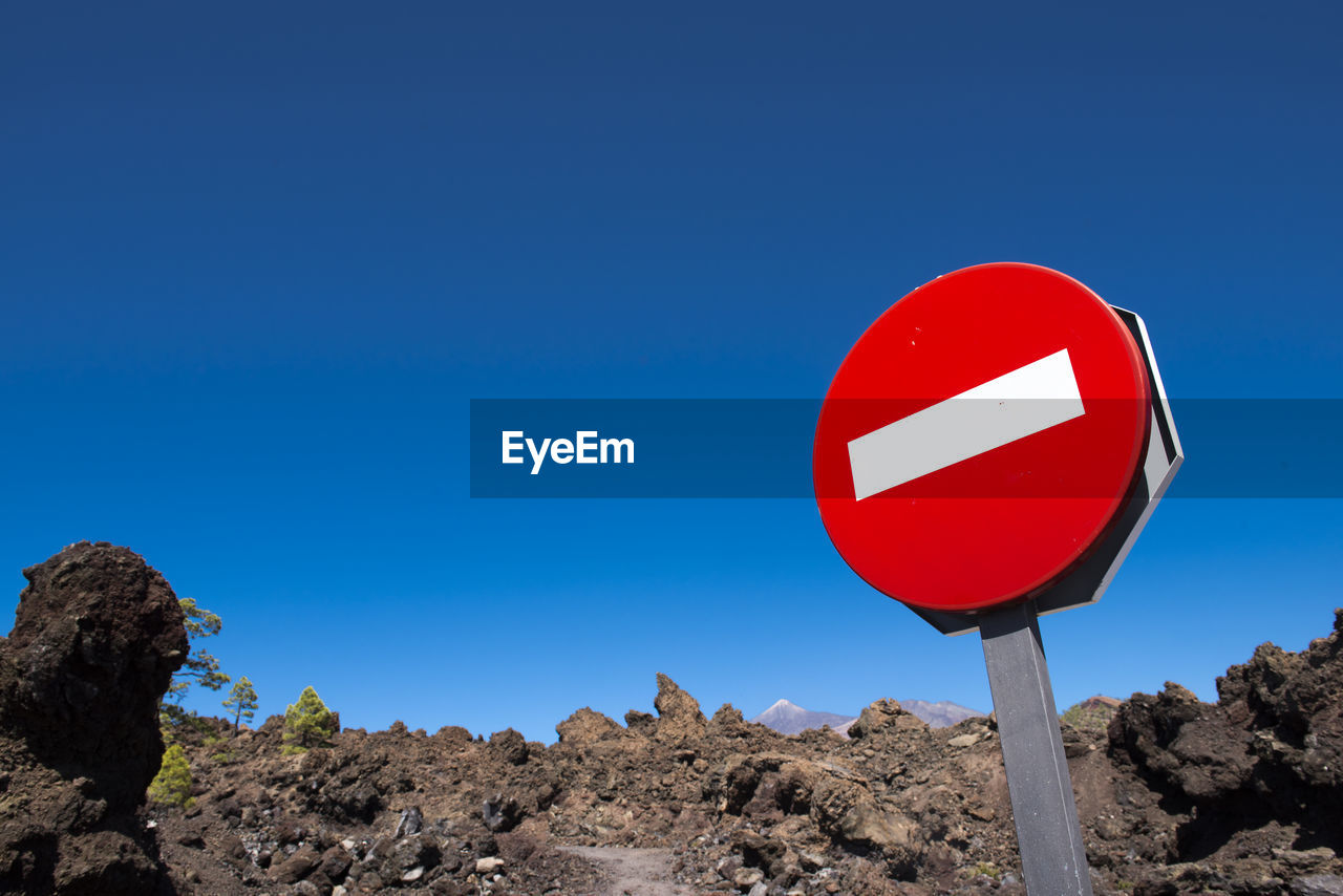 LOW ANGLE VIEW OF ROAD SIGNS AGAINST CLEAR BLUE SKY
