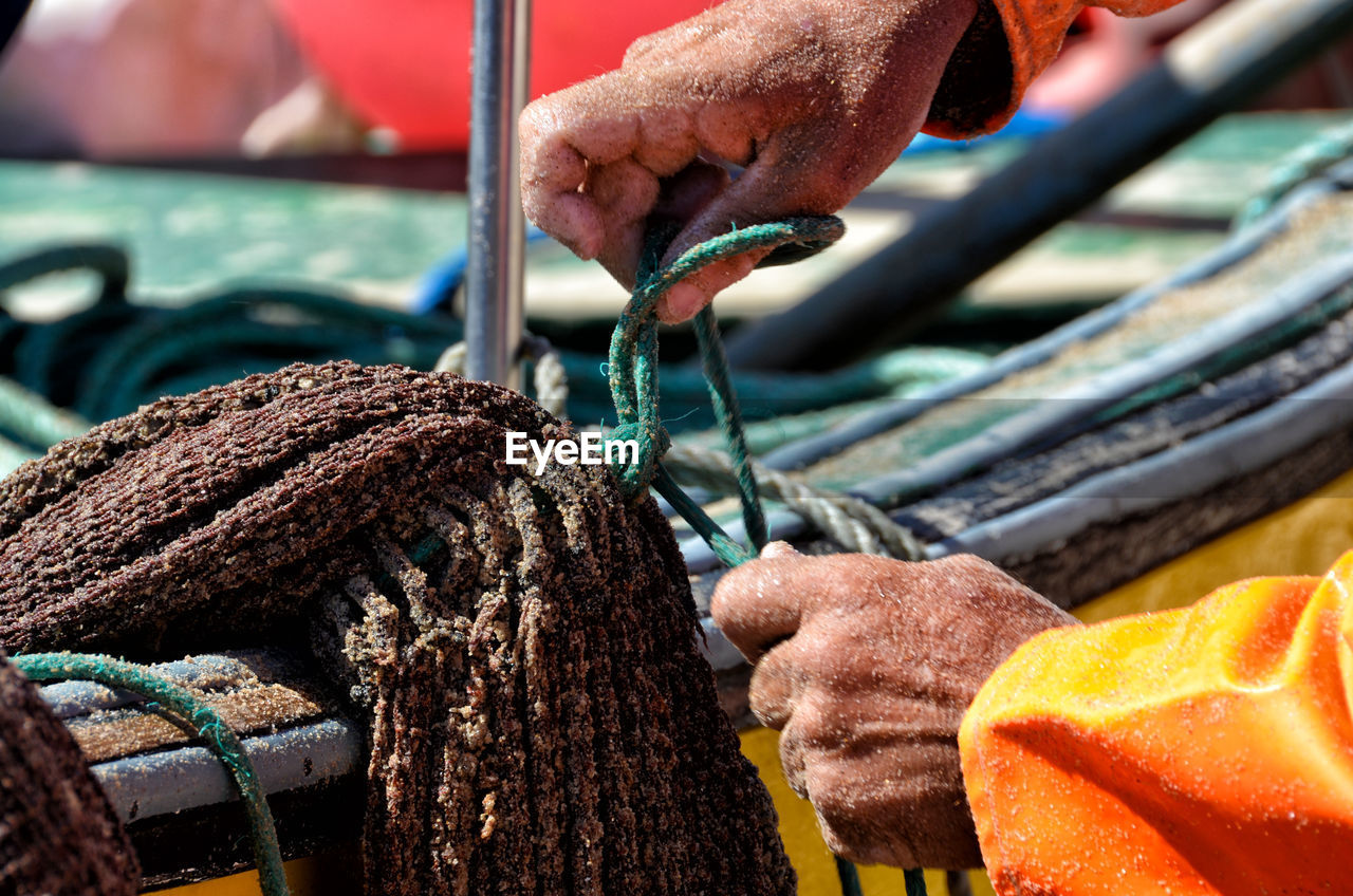 Cropped hands tying rope on boat